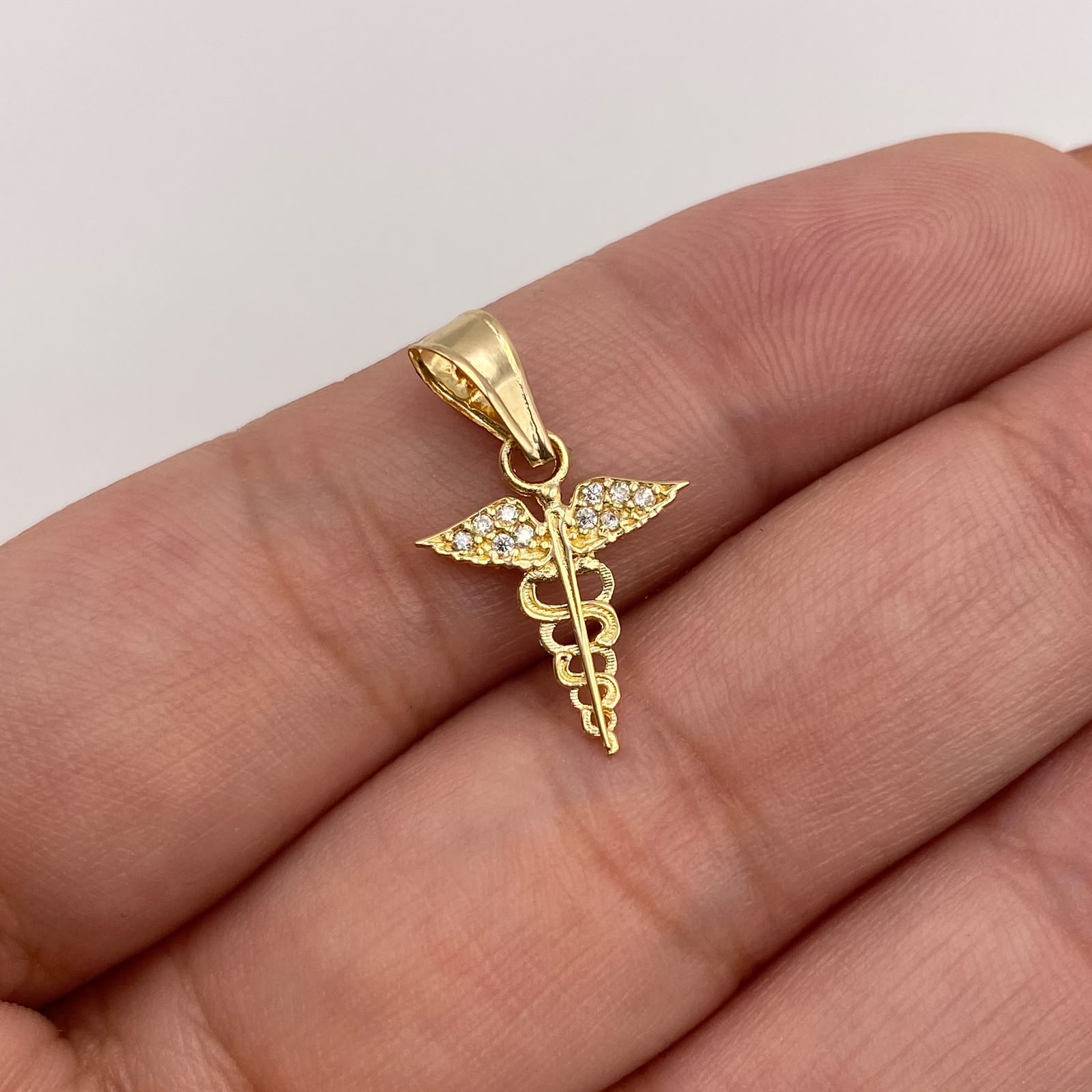 Dije Caduceo con alas y circones blancos Oro amarillo 18k 0,58 Gr / 12,55 mm / 2 Cm